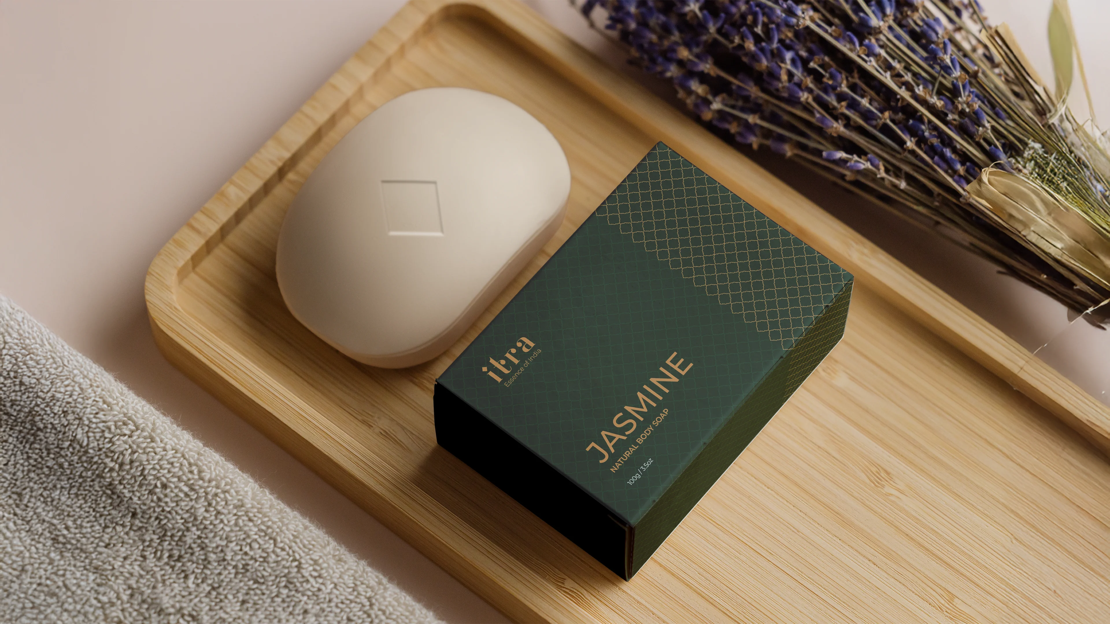 Itra Jasmine Natural Body Soap in a dark green drawer box with gold lattice pattern, alongside the soap bar on a bamboo tray with dried lavender